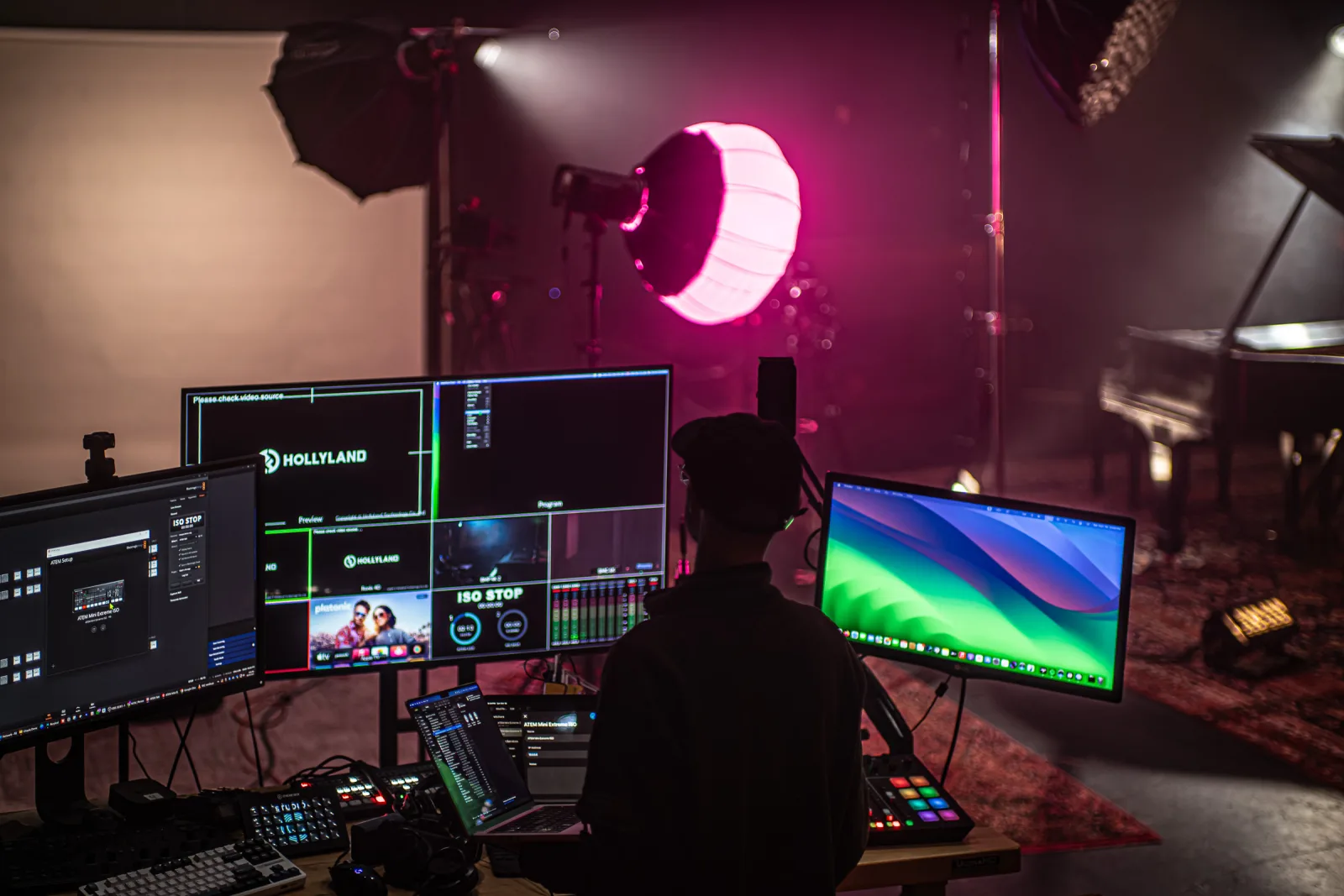 Studio C production station — monitors, ATEM switcher, and Steinway grand piano under magenta studio light